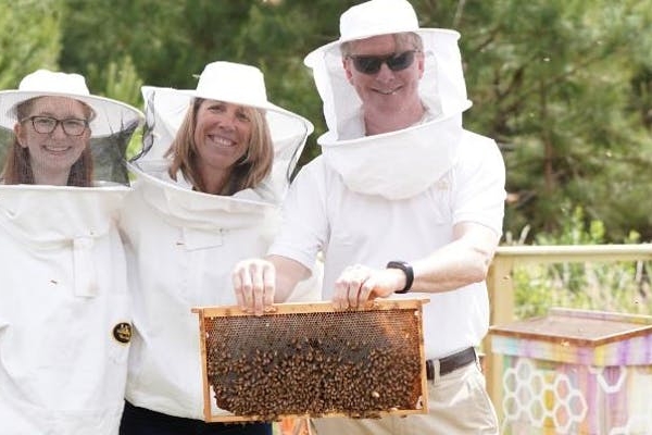 Bee hive tour picture of three attendees in their suit holding a hive